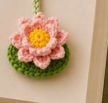 Layered pink crochet lotus flower with yellow center sewn on a green leaf pad